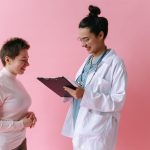 Médica conversa com uma paciente sorridente durante uma consulta em ambiente clínico.