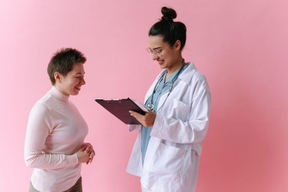 Médica conversa com uma paciente sorridente durante uma consulta em ambiente clínico.