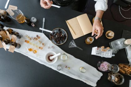 Vista superior de uma pessoa preparando perfume artesanal com ingredientes naturais sobre uma mesa de trabalho