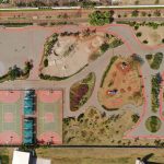 Vista aérea de um parque urbano colorido com quadras esportivas e áreas de recreação.