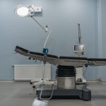 Sala de cirurgia moderna, vazia, equipada com mesa cirúrgica e aparelhos médicos.