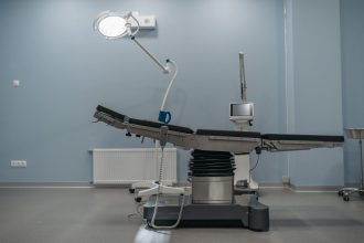 Sala de cirurgia moderna, vazia, equipada com mesa cirúrgica e aparelhos médicos.