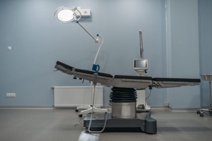 Sala de cirurgia moderna, vazia, equipada com mesa cirúrgica e aparelhos médicos.