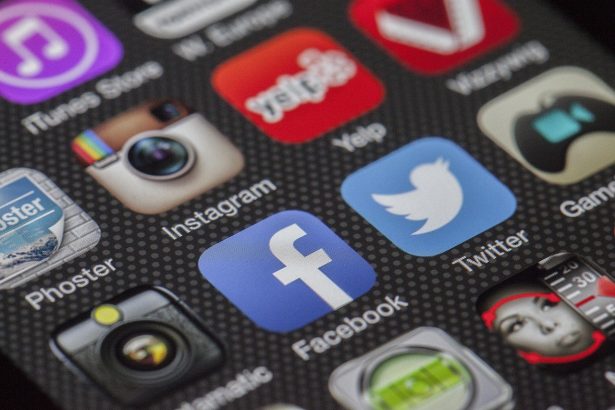 Smartphone exibindo ícones de aplicativos de redes sociais sobre fundo claro.