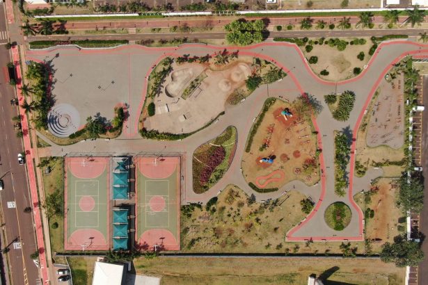 Vista aérea de um parque urbano colorido com quadras esportivas e áreas de recreação.